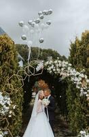 une Jeune mariage couple à une mariage La peinture cérémonie. le la mariée et jeune marié baiser contre le Contexte de des ballons en volant dans le ciel photo