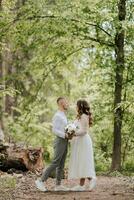 mariage marcher dans le forêt. le la mariée et jeune marié Regardez à chaque autre comme des arbres. rural mariage concept photo