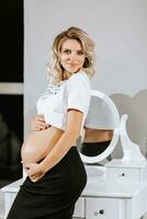 élégant studio portrait de une magnifique Enceinte Jeune femme contre une miroir Contexte photo