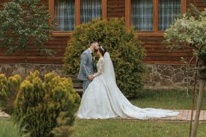 européen mariage couple dans le parc. le la mariée dans une magnifique robe avec manches et une couronne sur sa diriger. jeune marié avec une noir barbe de caucasien apparence dans une classique costume photo