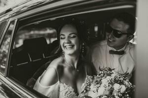 Jeune content la mariée et jeune marié sont réjouissance après le mariage la cérémonie dans leur voiture photo