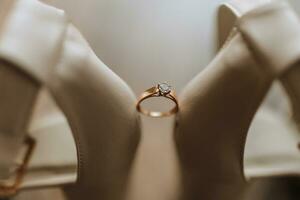 blanc mariage des chaussures et détails de le la mariée. une mariage bague avec une diamant est entre le de la mariée chaussures. mariage thème photo