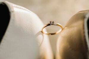 blanc mariage des chaussures et détails de le la mariée. une mariage bague avec une diamant est entre le de la mariée chaussures. mariage thème photo