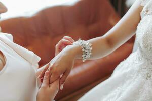 mariage thème. une ami met une bracelet sur le la mariée. quatre les brunes. le dernier minutes de les préparatifs pour le mariage. le même tenue photo