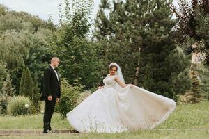 à la mode jeune marié et mignonne la mariée dans blanc robe avec couronne ayant amusement dans parc, jardin, forêt en plein air. mariage la photographie, grand angle photo