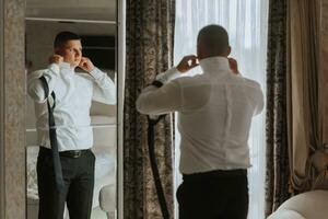 une élégant jeune marié est en train de préparer pour le mariage cérémonie. du marié Matin. homme d'affaire dans blanc chemise dans hôtel, Masculin mains fermer, jeune marié avoir prêt dans Matin avant mariage la cérémonie photo