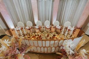 présidium de le la mariée et jeune marié à le mariage. tout est presque prêt pour le mariage fête. une mariage banquet, beaucoup fleurs, d'or couleurs, une riches et raffiné mariage photo