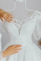 blanc mariage robe avec longue train dans pièce avec Accueil intérieur. le mains de le la mariée sont sur le robe avec une grand modèle photo