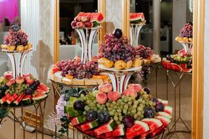 mariage décorations. réception. buffet. des fruits et fromage sur assiettes avec pain dans des boites. nourriture bar décoré par fleurs et lanternes photo