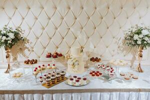 une délicieux mariage. beige gâteau décoré avec fleurs. bonbons bar avec divers Chocolat bonbons. fête concept. à la mode desserts. table avec bonbons, des sucreries. photo