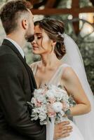 magnifique élégant luxueux la mariée avec voile soufflant dans le vent. et une élégant jeune marié baiser en plein air près grand l'automne des arbres photo