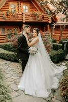 magnifique élégant luxueux la mariée avec voile soufflant dans le vent. et une élégant jeune marié baiser en plein air près grand l'automne des arbres photo