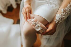 le la mariée dans une blanc peignoir porte une beige jarretière sur sa jambe. soumissionner Matin de le la mariée. photo