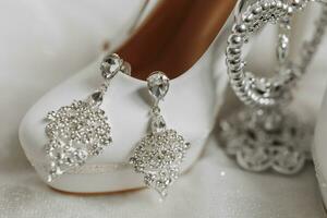 mariage des chaussures de le la mariée avec des boucles d'oreilles sur le train de le mariage robe photo