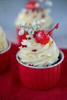 petits gâteaux avec Cerise sur une rouge serviette de table sur une blanc Contexte photo