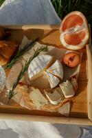 Camembert fromage avec pamplemousse et Romarin sur une en bois planche photo