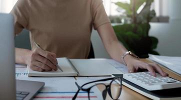 fermer les femmes à l'aide de la calculatrice et noter certaines données sur le bloc-notes photo