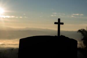 silhouette de croix catholique et lever de soleil photo