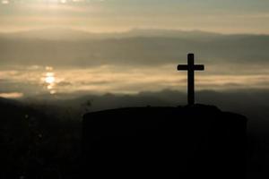 silhouette de croix catholique et lever de soleil photo