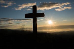 silhouette de croix catholique et lever de soleil photo