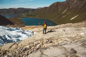 homme avec un sac à dos debout sur un rocher sur fond de montagne et de lac photo