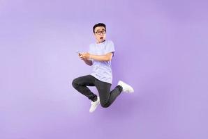 Portrait d'un homme asiatique sautant, isolé sur fond violet