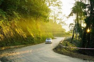 image de la route de montagne de la montagne ba vi, les rayons du soleil percent les arbres, les voitures roulent sur la route photo