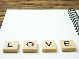 mot d'amour dans un cube en bois et un cahier et un stylo sur fond noir en bois, saint valentin photo