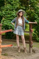 adolescent brunette permanent près clôture de stable dans rural Manoir dans été photo