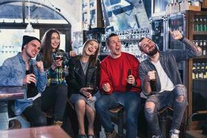 groupe de Jeune magnifique copains en train de regarder la télé et applaudissement pour e photo