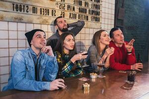 groupe de Jeune magnifique copains en train de regarder la télé et applaudissement pour e photo