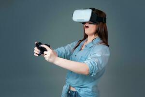 émotif Jeune femme en utilisant une vr casque et expérience virtuel réalité sur gris Contexte photo
