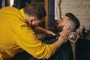 client avec gros noir barbe pendant barbe rasage dans coiffeur magasin photo