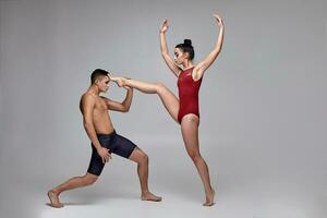 le couple de un athlétique moderne ballet danseurs sont posant contre une gris studio Contexte. photo