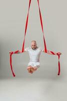athlétique homme dans une blanc sport costume est performant un acrobatique éléments dans une studio. photo