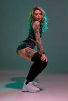 sexy blond femme avec tatoué corps et longue frisé cheveux est dansant twerk dans studio. photo