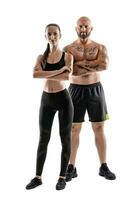 athlétique homme dans noir short et baskets avec brunette femme dans leggings et Haut posant isolé sur blanc Contexte. aptitude couple, Gym concept. photo