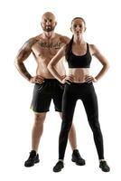 athlétique homme dans noir short et baskets avec brunette femme dans leggings et Haut posant isolé sur blanc Contexte. aptitude couple, Gym concept. photo