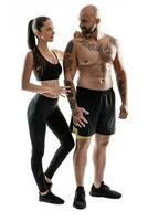 athlétique homme dans noir short et baskets avec brunette femme dans leggings et Haut posant isolé sur blanc Contexte. aptitude couple, Gym concept. photo