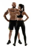 athlétique homme dans noir short et baskets avec brunette femme dans leggings et Haut posant isolé sur blanc Contexte. aptitude couple, Gym concept. photo