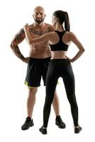 athlétique homme dans noir short et baskets avec brunette femme dans leggings et Haut posant isolé sur blanc Contexte. aptitude couple, Gym concept. photo