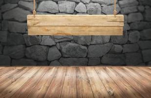 table en bois avec panneau en bois suspendu sur mur de pierre photo