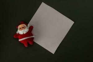 Père Noël claus avec blanc feuille de papier sur une noir arrière-plan, copie espace photo