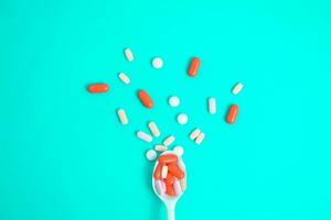 coloré médicament pilules dans blanc cuillère sur vert tosca arrière-plan, supplément, vitamine, coloré photo