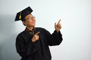 expressif de adulte Indonésie Masculin porter l'obtention du diplôme peignoir, chapeau et lunettes isolé sur blanc arrière-plan, expressions de portrait l'obtention du diplôme photo