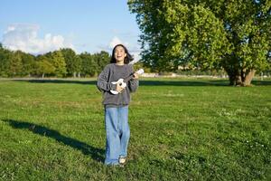 content Jeune femme sentiment insouciant, en marchant dans vert parc et en jouant ukulélé, en chantant le long de photo