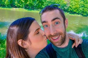 heureux jeune couple prenant un selfie avec un smartphone ou un appareil photo dans le parc