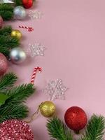 décorations de noël, feuilles de pin, boules dorées, flocons de neige, boules rouges sur fond rose photo