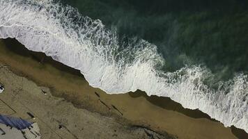 le sable plage. action. Haut vue de une magnifique sablonneux plage avec le bleu vagues roulant dans le rive. mer Contexte photo