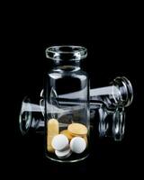 verre transparent bouteilles avec pilules à l'intérieur. pilules isolé sur une noir Contexte. photo